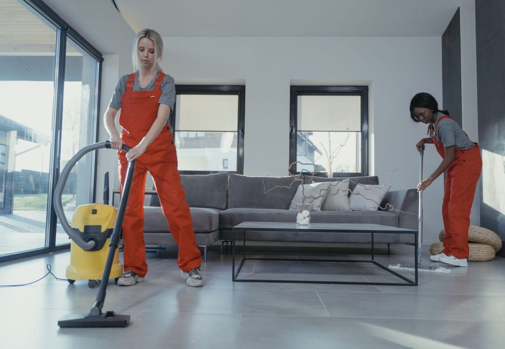 Cleaners vacuuming and mopping a tidy living room during a regular house clean